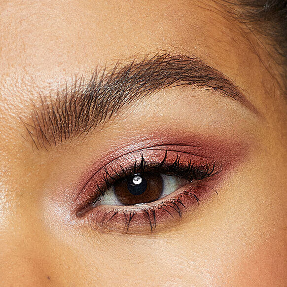 Close-up of a woman's eye with Vieve pink eyeshadow and long eyelashes.