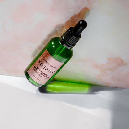 Votary Brightening Hyaluronic Serum 50ml on a light background with a pipette, showcasing its vibrant green bottle.