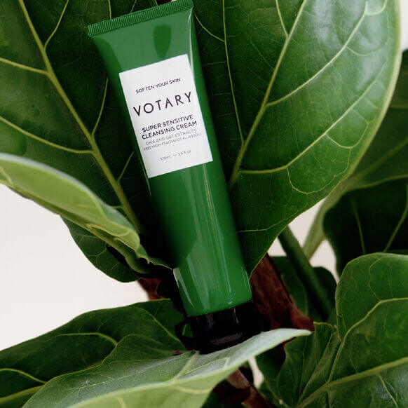 VOTARY Super Sensitive Cleansing Cream tube nestled among lush green leaves, showcasing gentle skincare for sensitive skin.