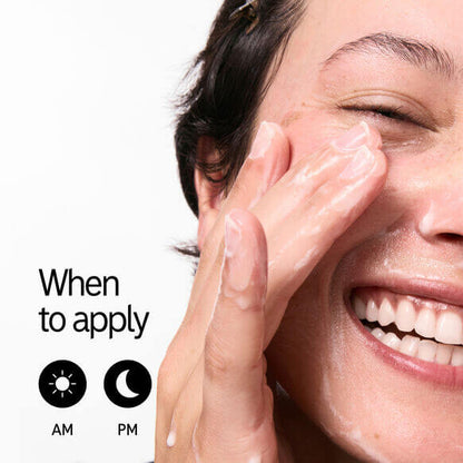 Woman happily applying cleanser to her face, indicating morning and evening use of a skincare product.