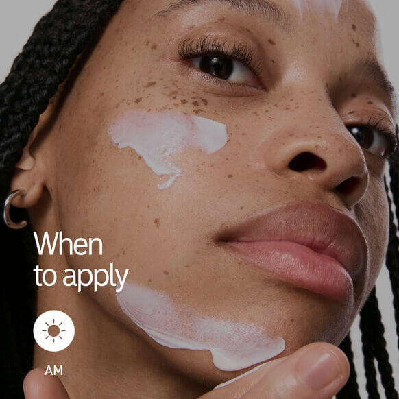 Woman applying sunscreen to her face, indicating the best time for application in the morning.