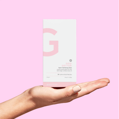 Hand holding a ZITSTICKA skincare product box with a pink background