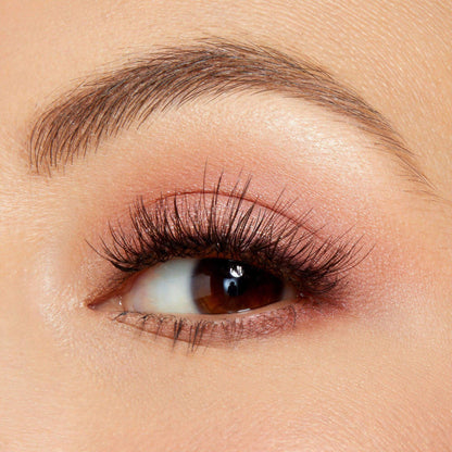 Close-up of an eye showcasing soft pink eyeshadow and voluminous lashes, perfect for warm-toned looks.