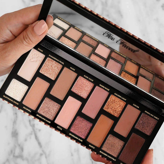 Too Faced Born This Way The Natural Nudes Eyeshadow Palette showing 16 pigmented shades in a hand-held view.