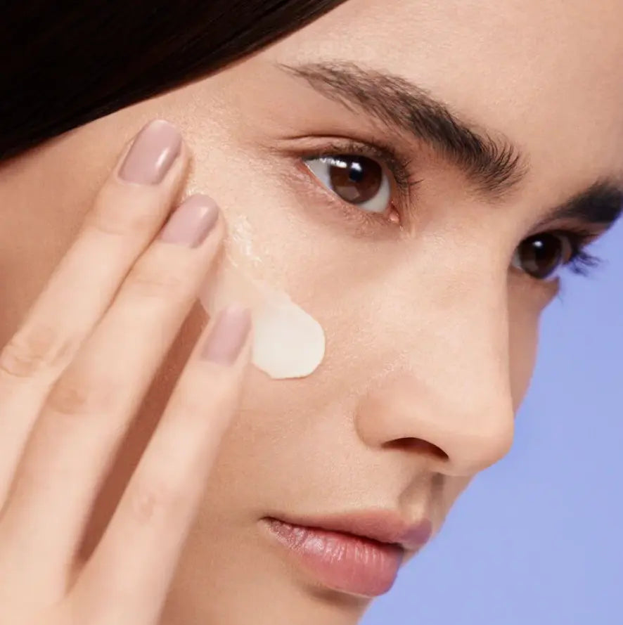 Model applying Shiseido Vital Perfection Uplifting and Firming Cream on her face for a rejuvenated complexion.