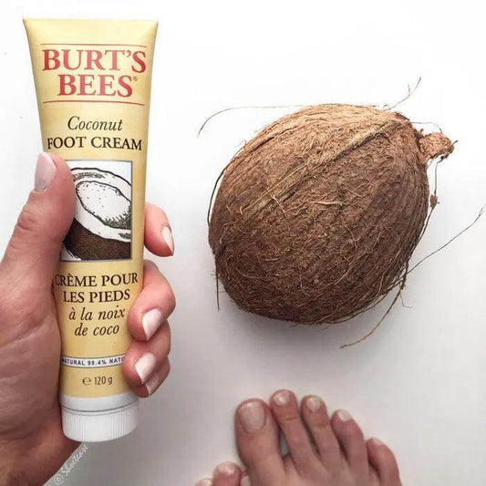 Burt's Bees Coconut Foot Cream 120g tube next to a coconut and a person's foot, showcasing moisturizing foot care.