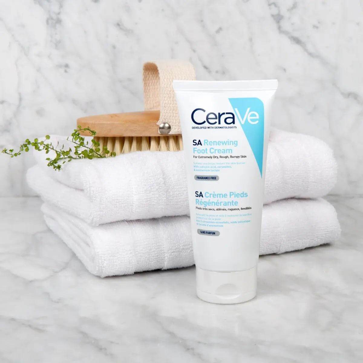 CeraVe SA Renewing Foot Cream 88ml on a marble countertop with towels and a brush, ideal for exfoliation and hydration.