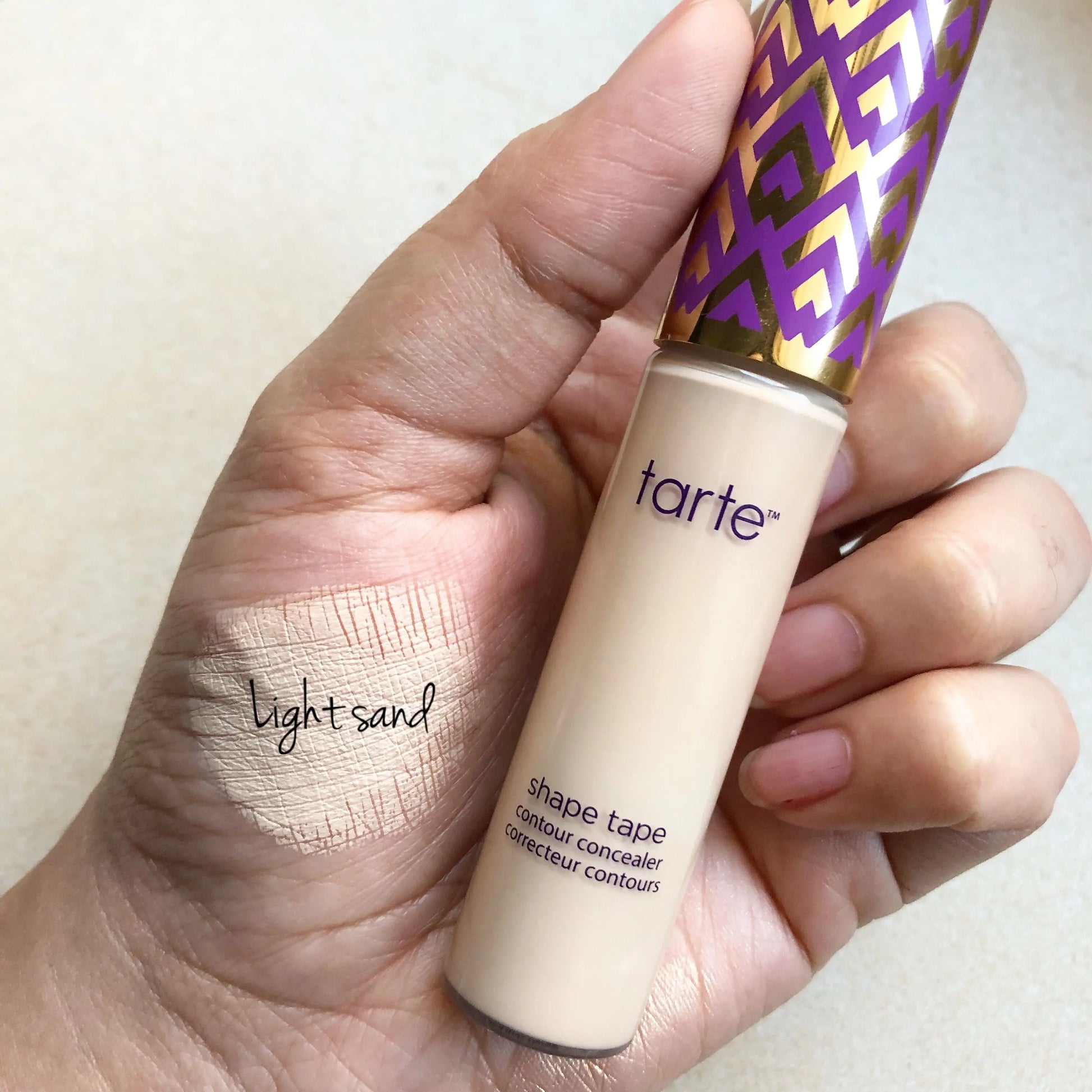 TARTE Shape Tape Concealer in Light Sand shown in hand, with blendable formula for brightening and smoothing skin.