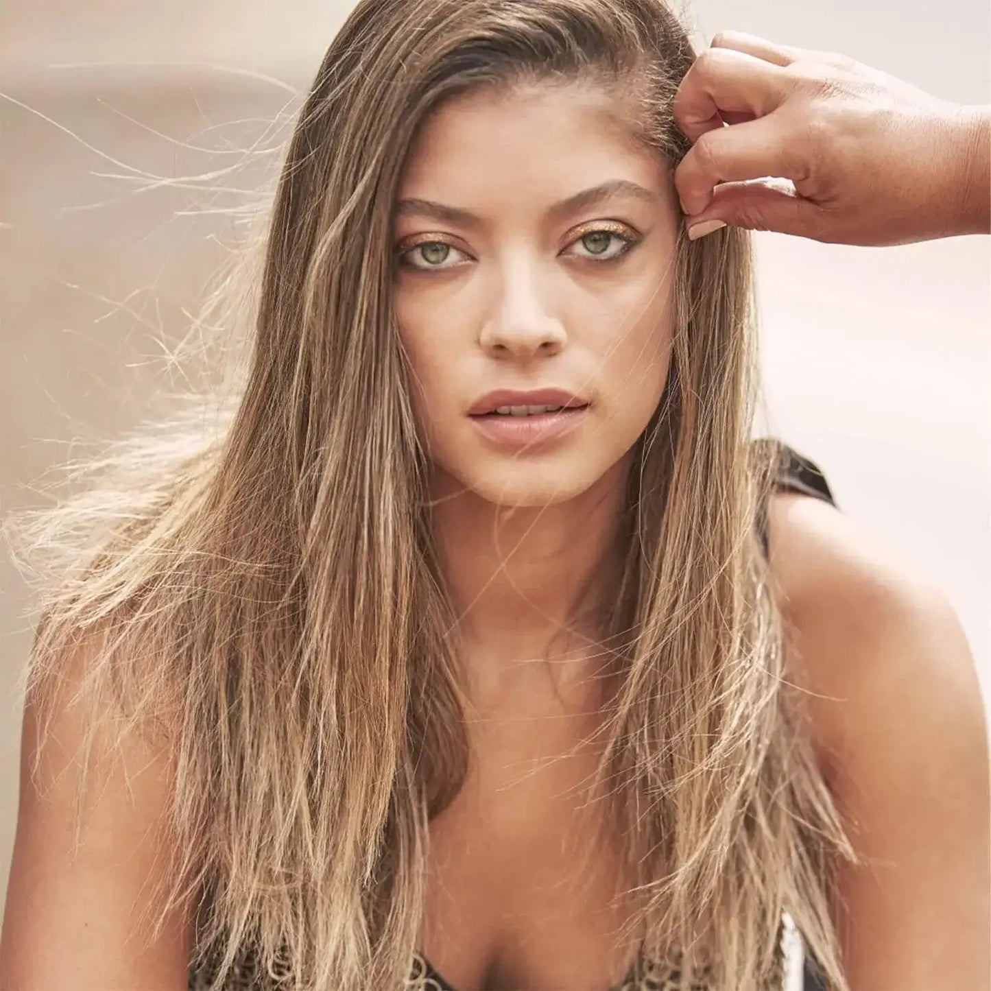 Bumble and bumble Model with long, straight hair looking directly at the camera, with a stylist's hand adjusting her hair.