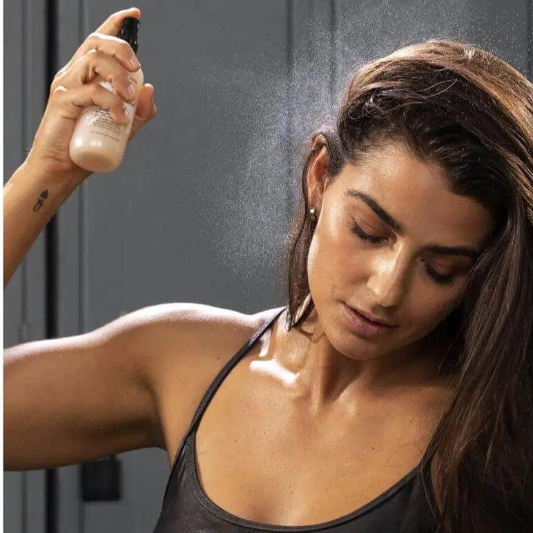 Model using Bumble & Bumble Prêt-à-powder Dry Shampoo Mist to refresh sweaty hair after a workout.