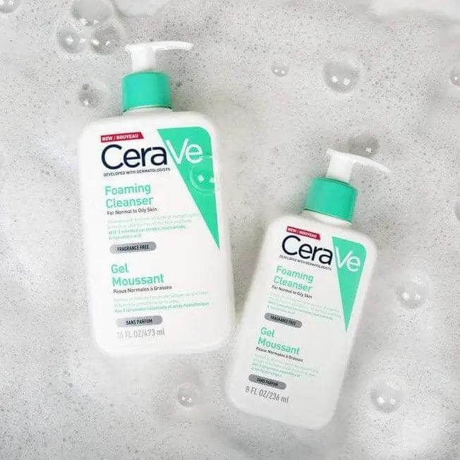 CeraVe Foaming Cleanser 473ml and 236ml bottles on a soapy surface, designed for oily to normal skin types.