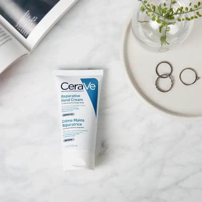 CeraVe Soothing & Repairing Hand Cream 50ml on a marble surface with accessories, promoting skin barrier protection.