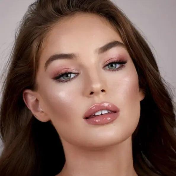 Model showcasing Charlotte Tilbury Lip Lustre with glossy nude-pink lips and radiant skin.
