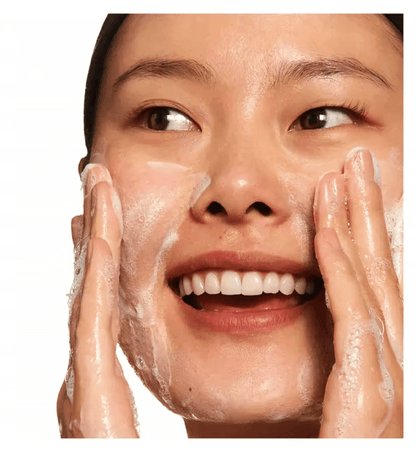 Woman cleansing her face with foamy cleanser, demonstrating a skincare routine for healthy skin.