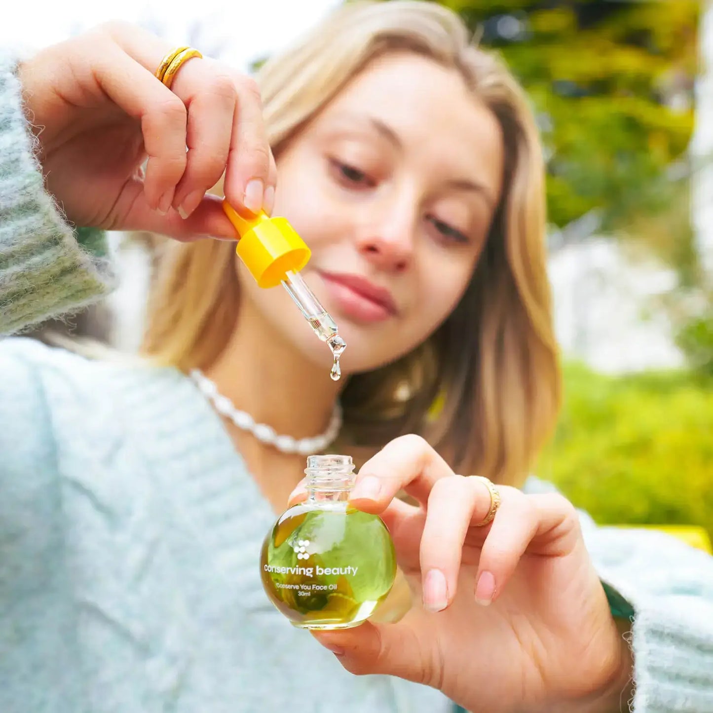 Woman applying Conserving Beauty Conserve You Face Oil with a dropper for radiant skin and youthful glow.