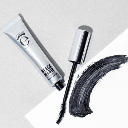 Eyeko Black Magic Mascara with applicator next to a bold stroke of black mascara on a light background.