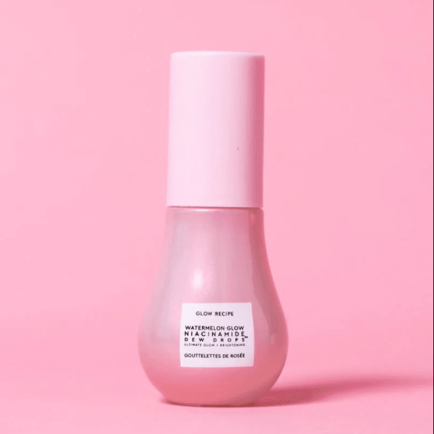 Glow Recipe Watermelon Glow Niacinamide Dew Drops highlighter bottle against a pink background, showcasing skincare and radiance.