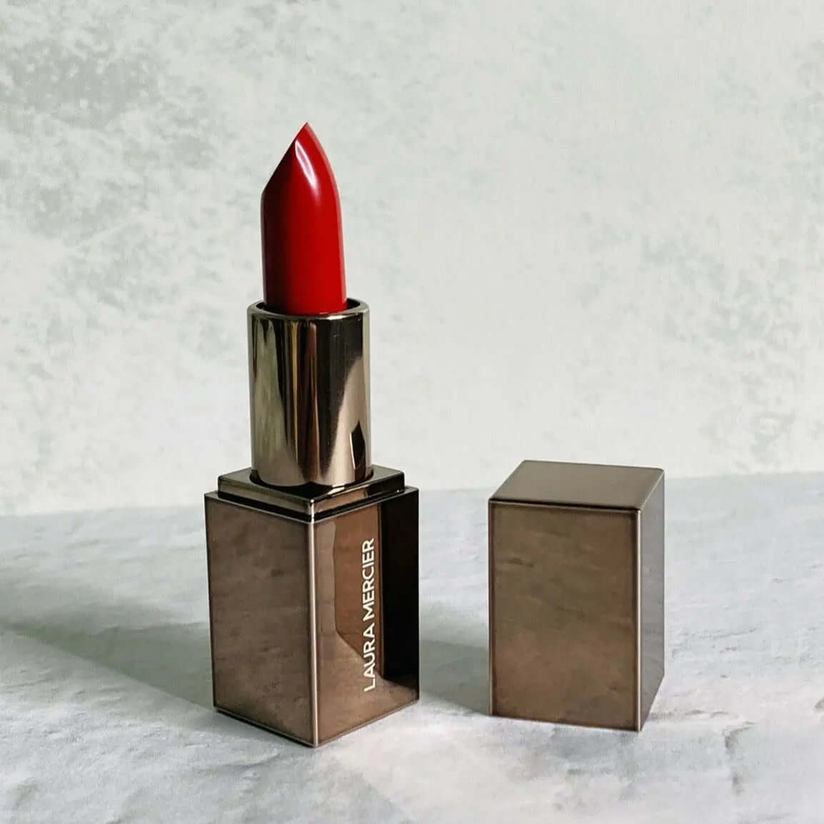 Laura Mercier Rouge Essentiel Silky Crème Mini Lipstick in Rouge Ultime, medium-dark red lipstick in sleek metallic case.
