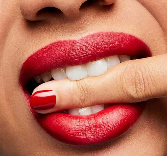 Close-up of lips wearing MAC Ruby Woo lipstick with bold matte finish and manicured red nails.