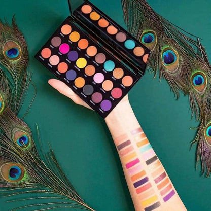 Makeup Revolution Creative Vol 1 Palette with 24 vibrant shades held above arm showcasing colorful swatches.