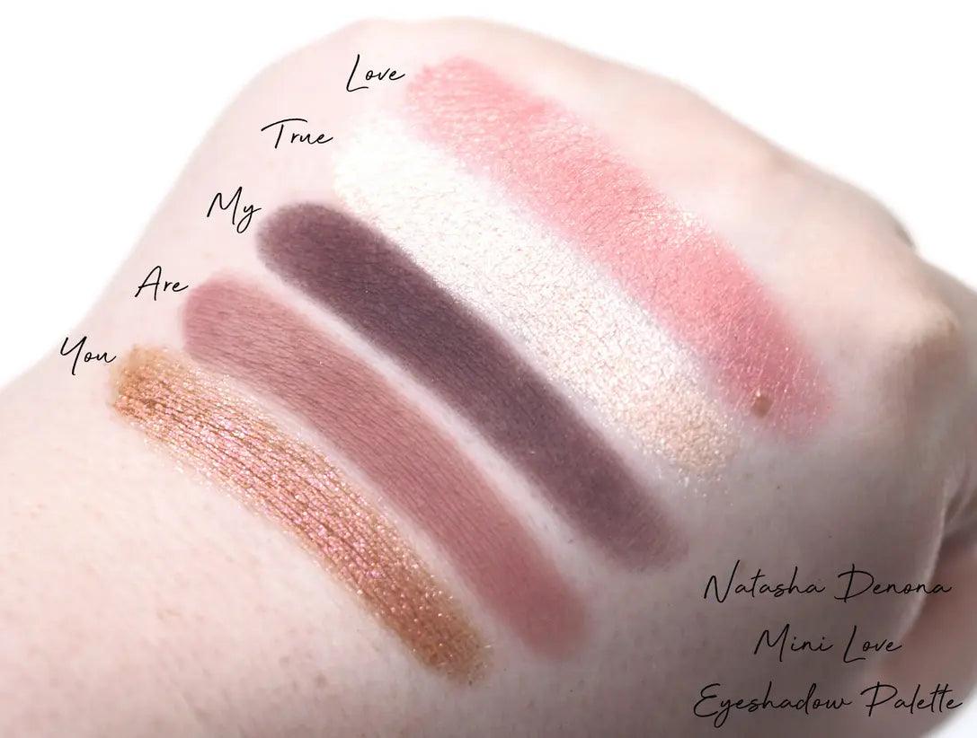 Swatches of Natasha Denona Mini Love Eyeshadow Palette showcasing five pink and lilac shades on skin.