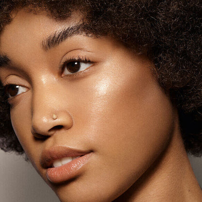 Close-up of a woman showcasing glowing skin, enhanced by VIEVE Skin Dew highlighter, promoting radiant beauty.